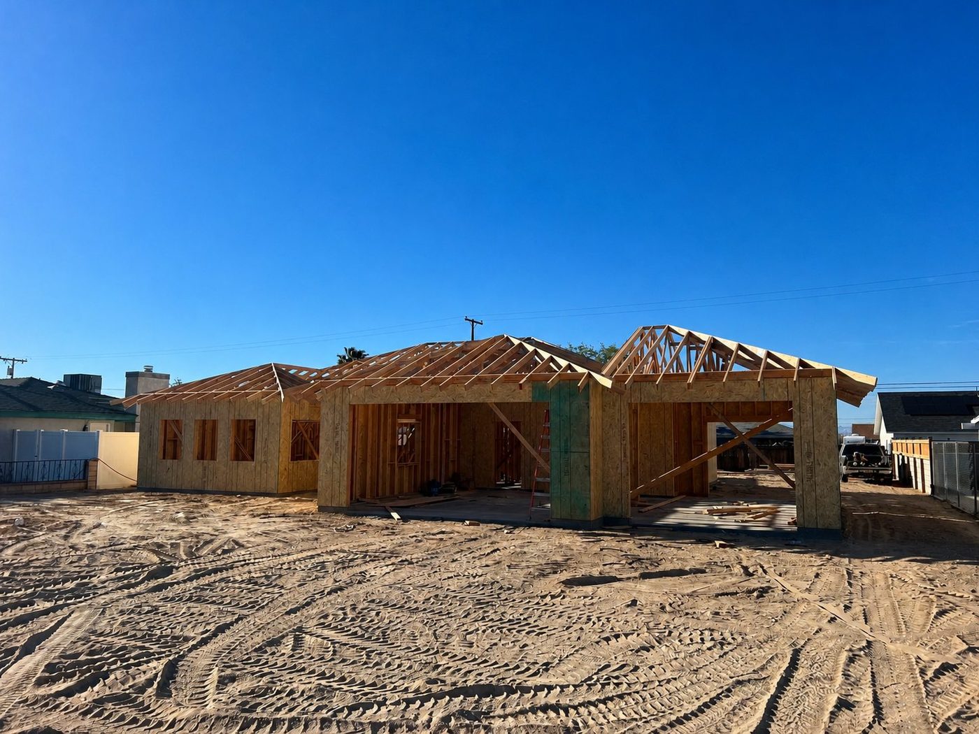 Custom home under construction with wall sheathing, roof rafters, and wood trusses installed