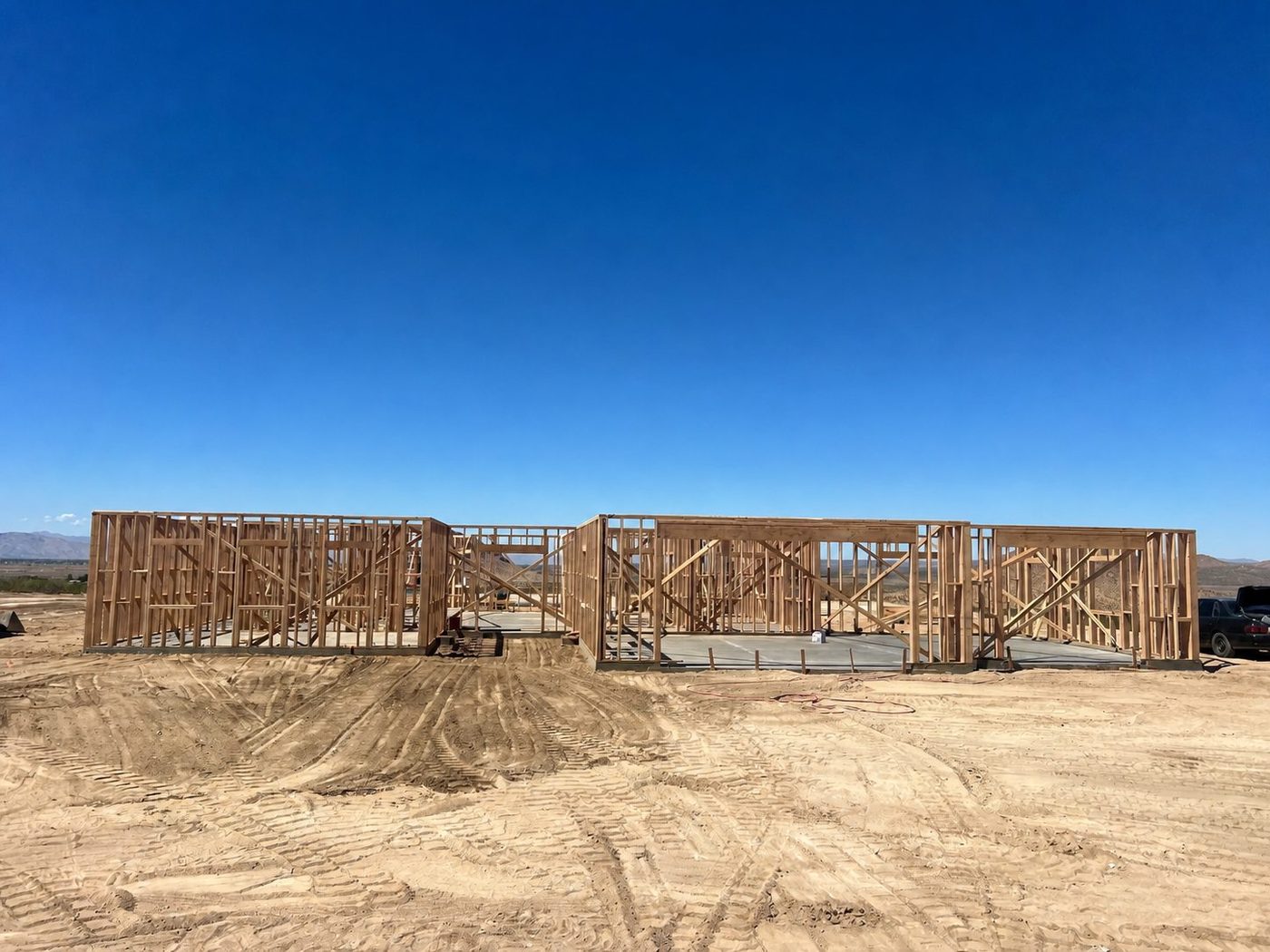 Wood-framed walls of a custom residential home under construction at a desert job site
