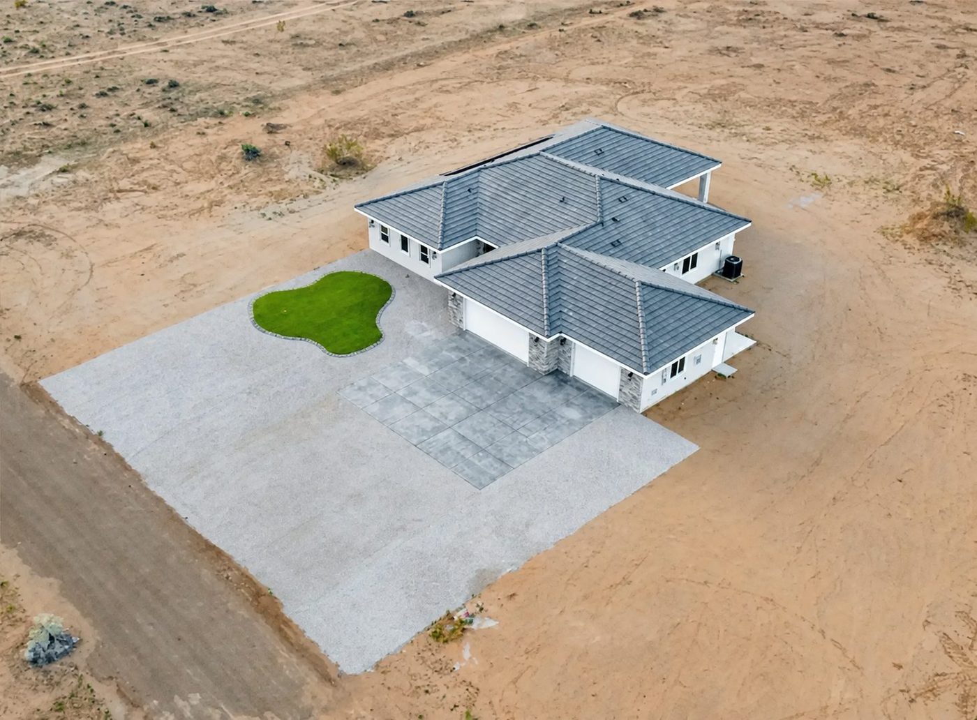 Aerial view of a finished custom residence and its concrete driveway on desert acreage