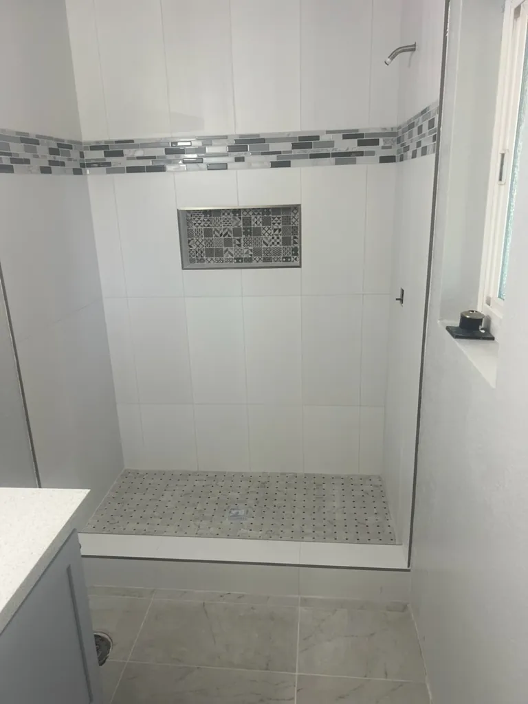 Completed custom shower with glass doors and a tile accent niche