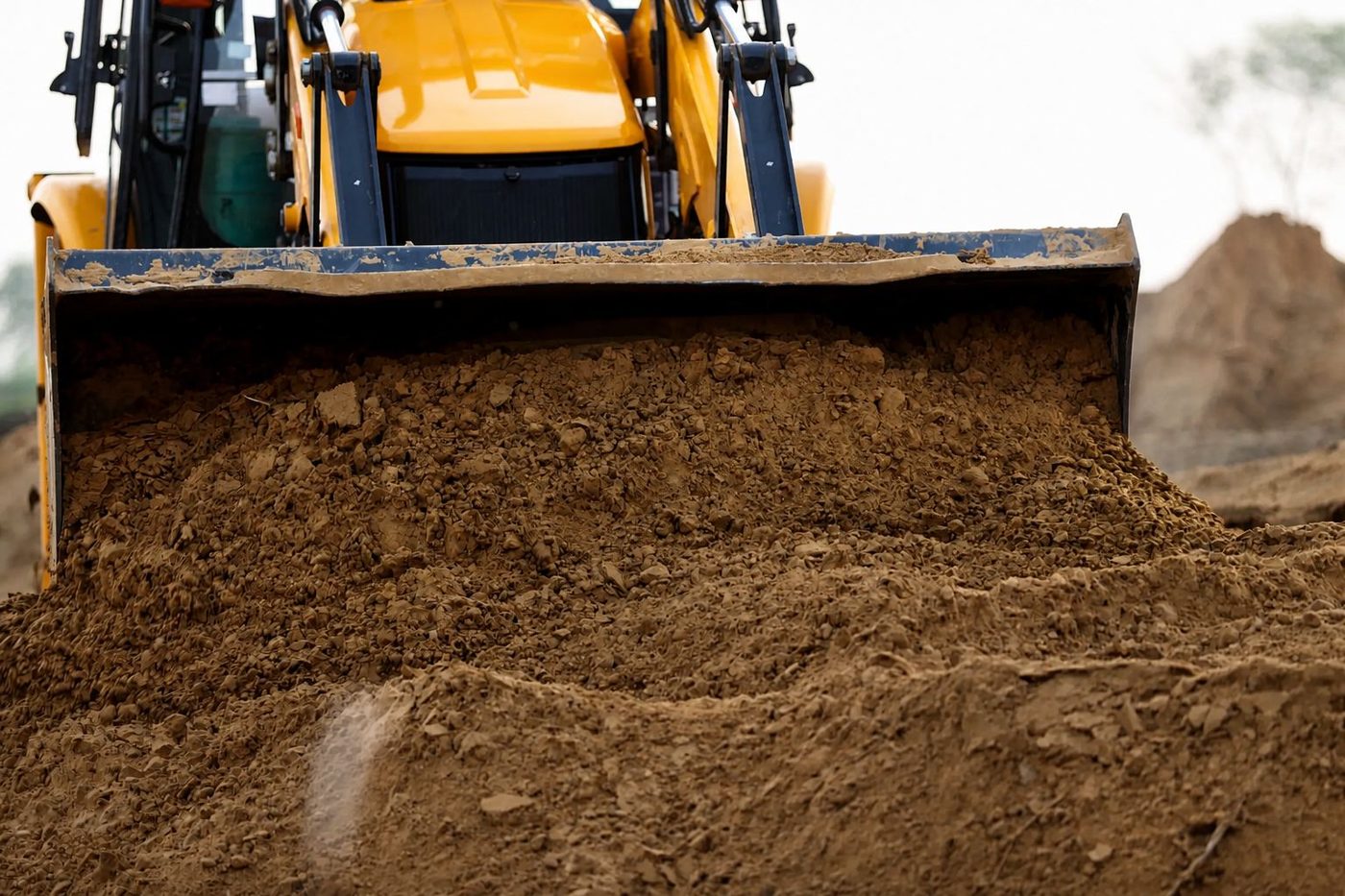 Front loader pushing and grading soil at a construction site