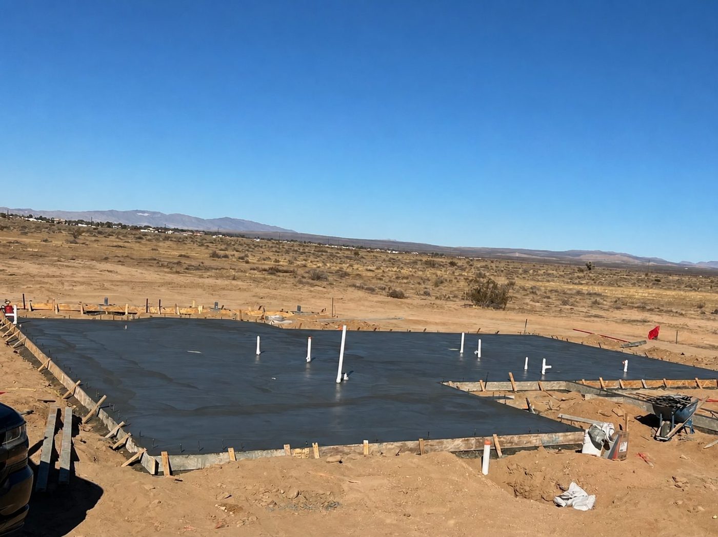 Freshly poured concrete foundation slab with plumbing stub-ups and perimeter forms