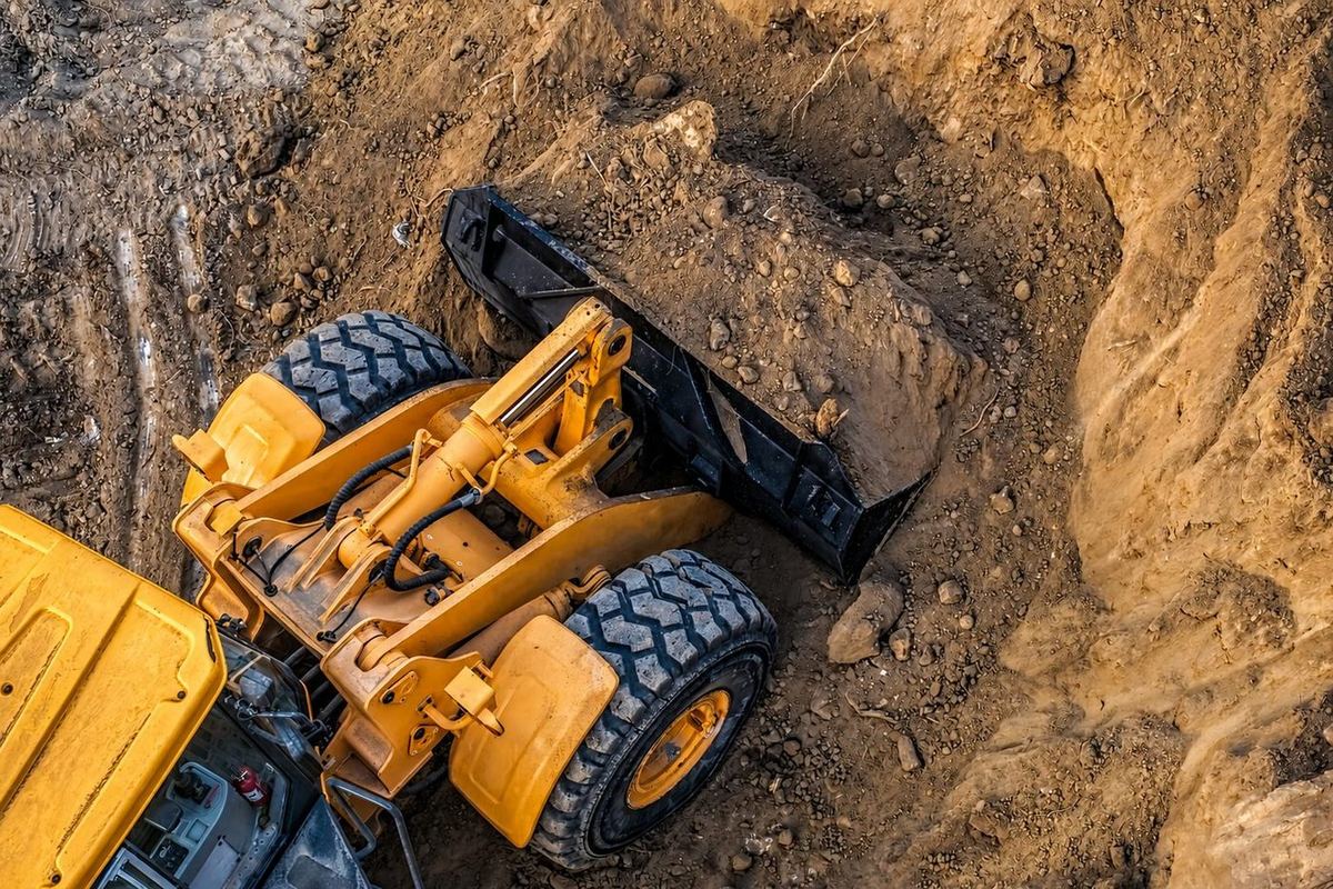 Wheel loader excavating soil and rock in a utility trench